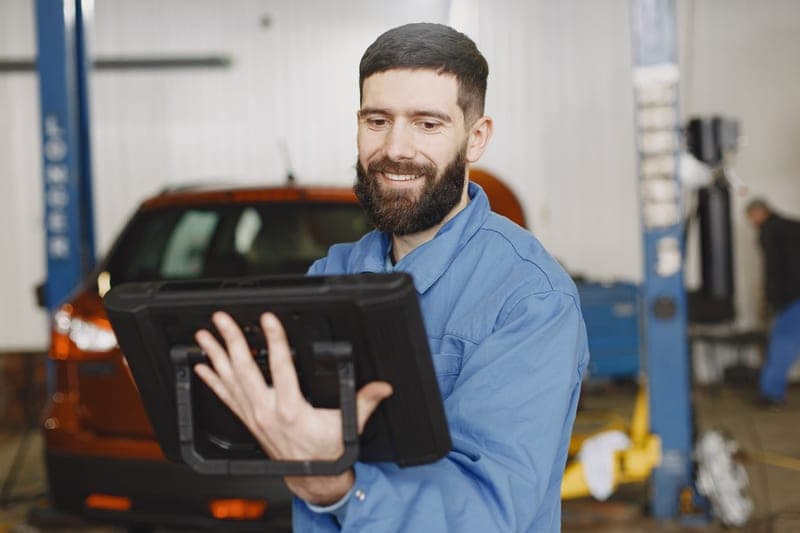 A mechanic using a digital tablet for vehicle diagnostics in a garage